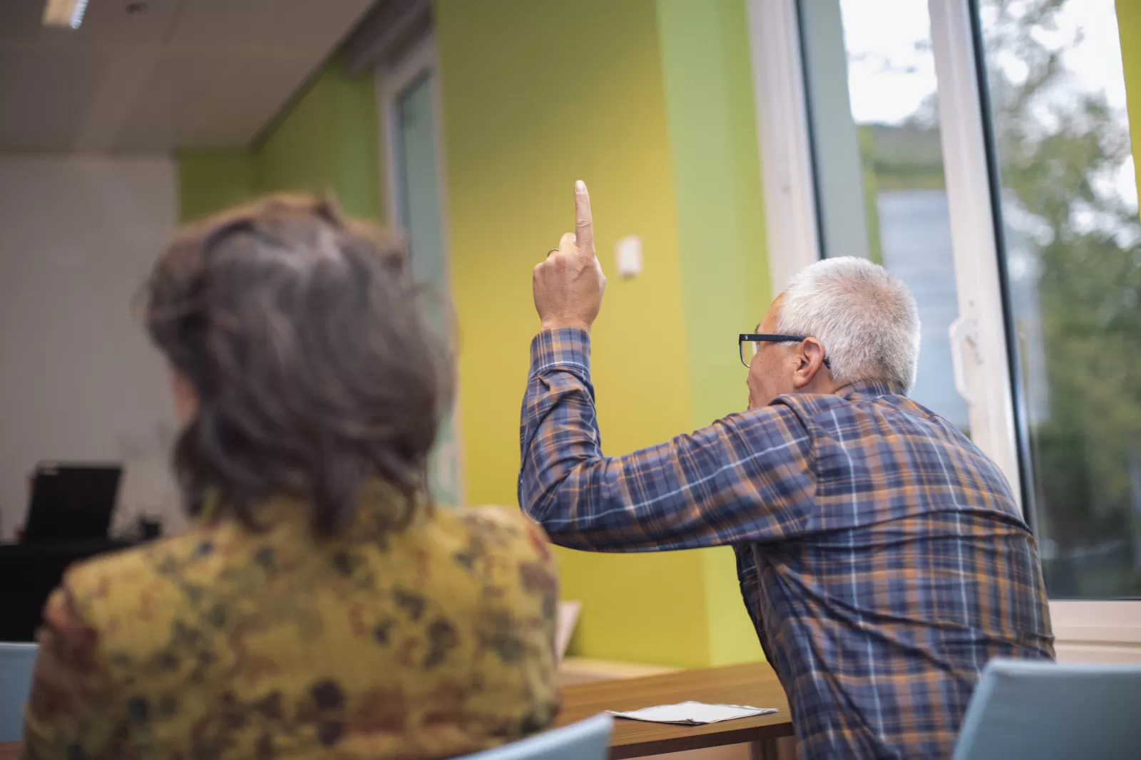 Een deelnemer van het Artrose Café steekt zijn hand op om een vraag te stellen